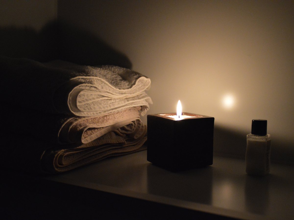 Toallas dobladas y vela encendida en un spa en penumbra