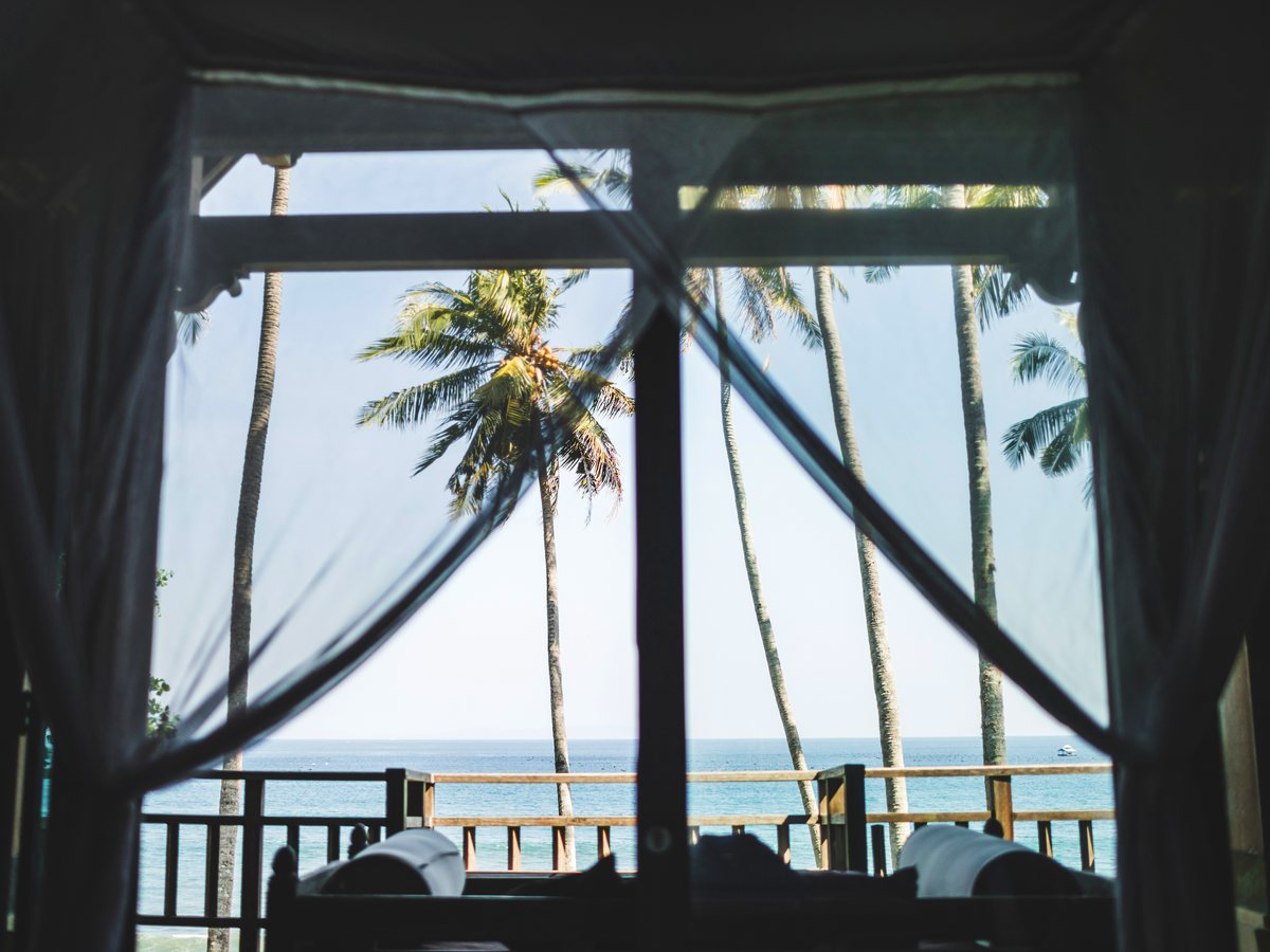 Ventana de villa frente al mar con palmeras
